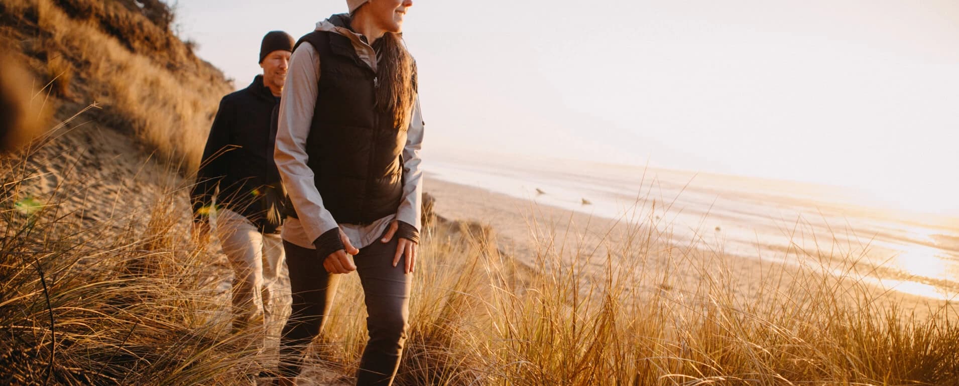Couple walking along a coastal dune trail at sunset