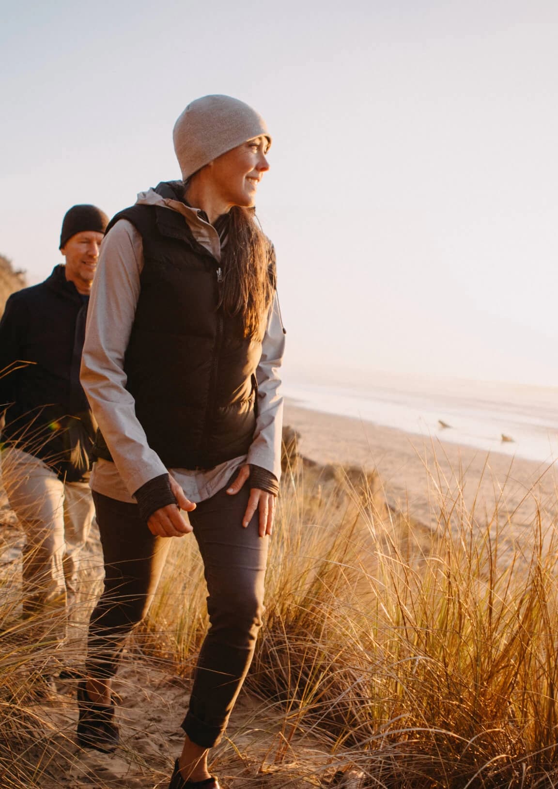 Couple walking along a coastal dune trail at sunset